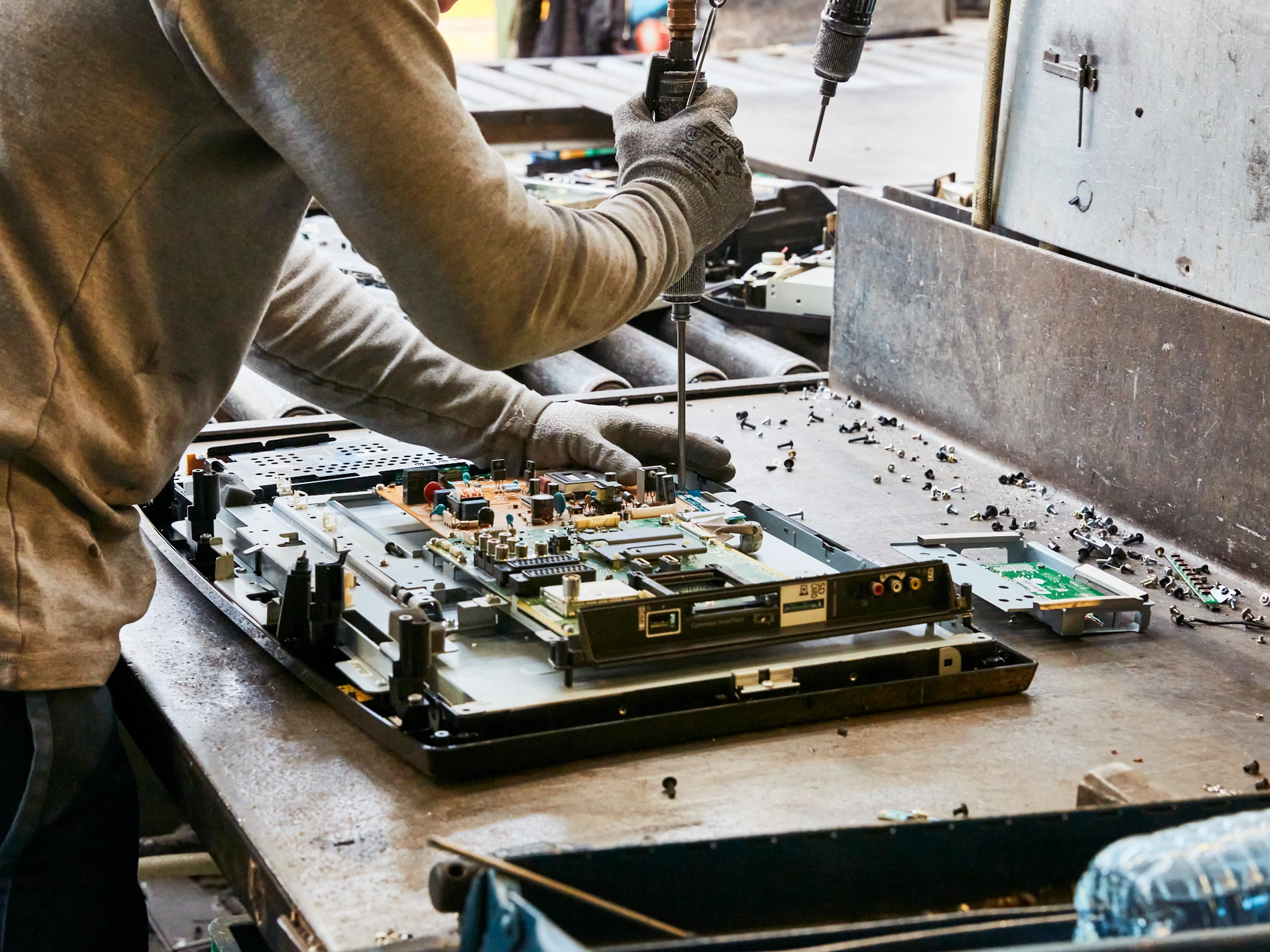 Demontage van flatscreentelevisie op werkbank; schroeven en printplaten worden verwijderd