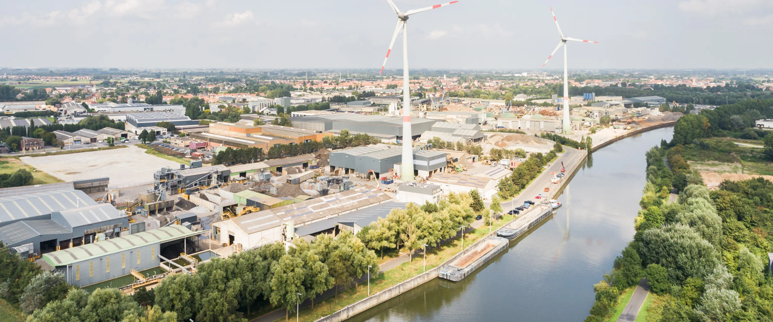 Luchtfoto van de Galloo-site Menen aan het kanaal met twee windturbines en een binnenschip