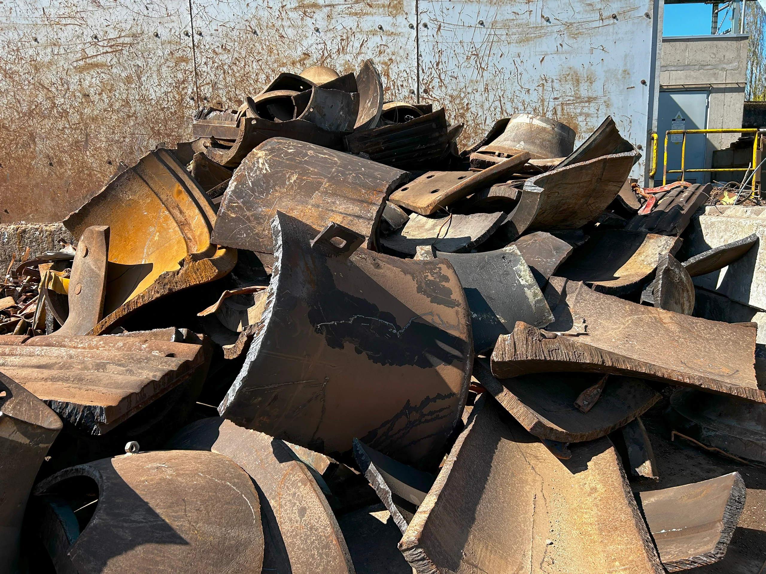 Stapel zware, roestige staalstukken en uitgesneden platen op het terrein